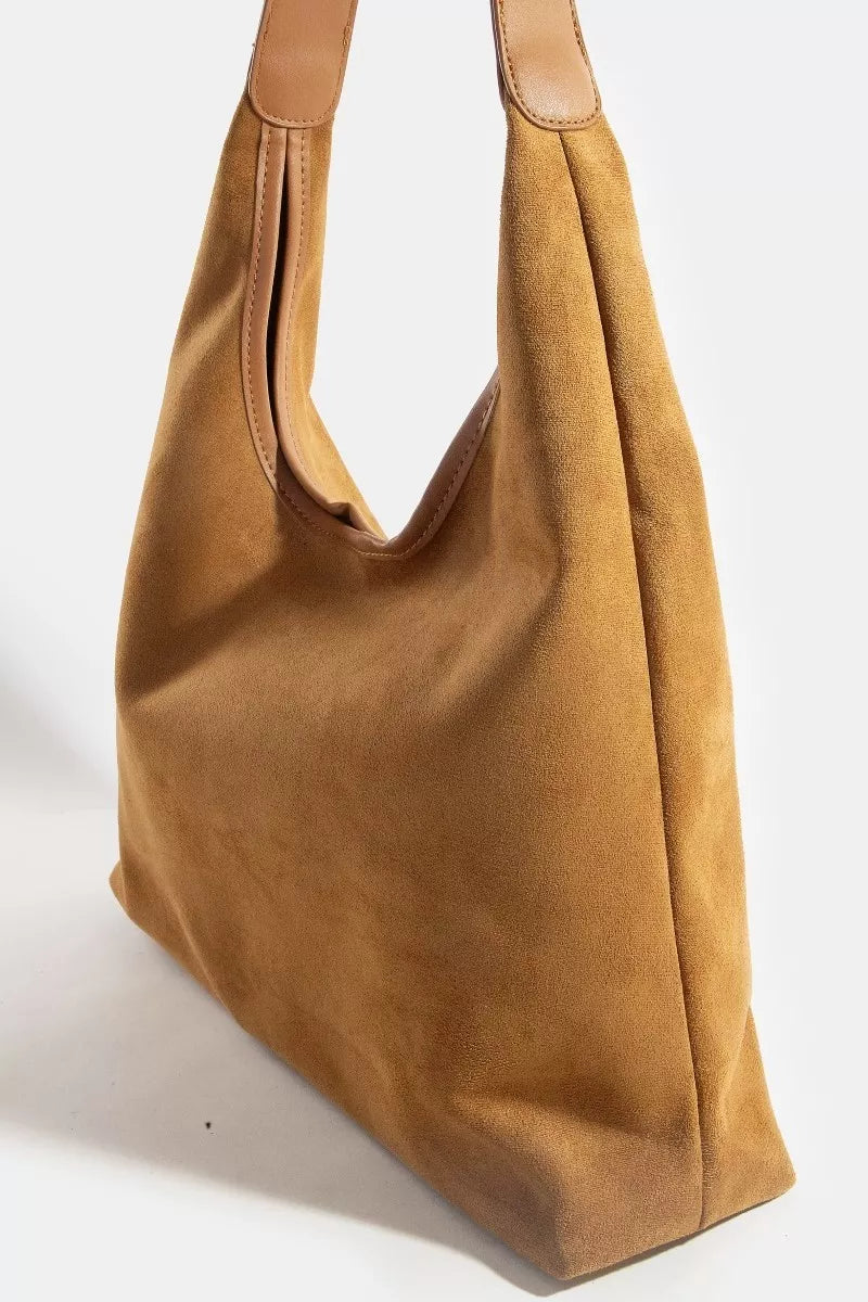 Brown suede handbag with tan leather handles on a white background