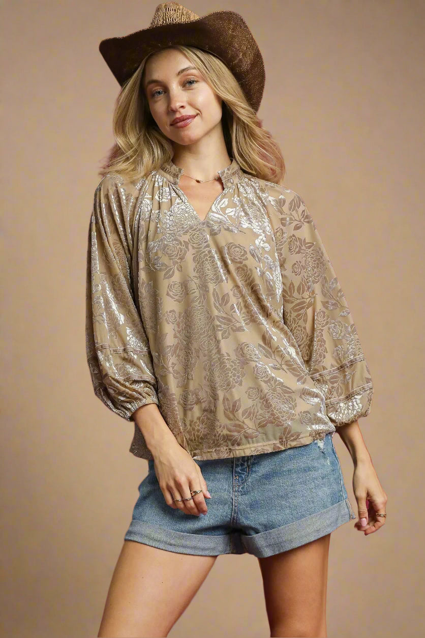 Woman wearing a patterned blouse and denim shorts with a cowboy hat on a beige background