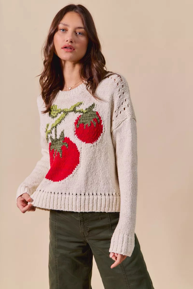 Woman wearing a white sweater with red apple designs on a beige background