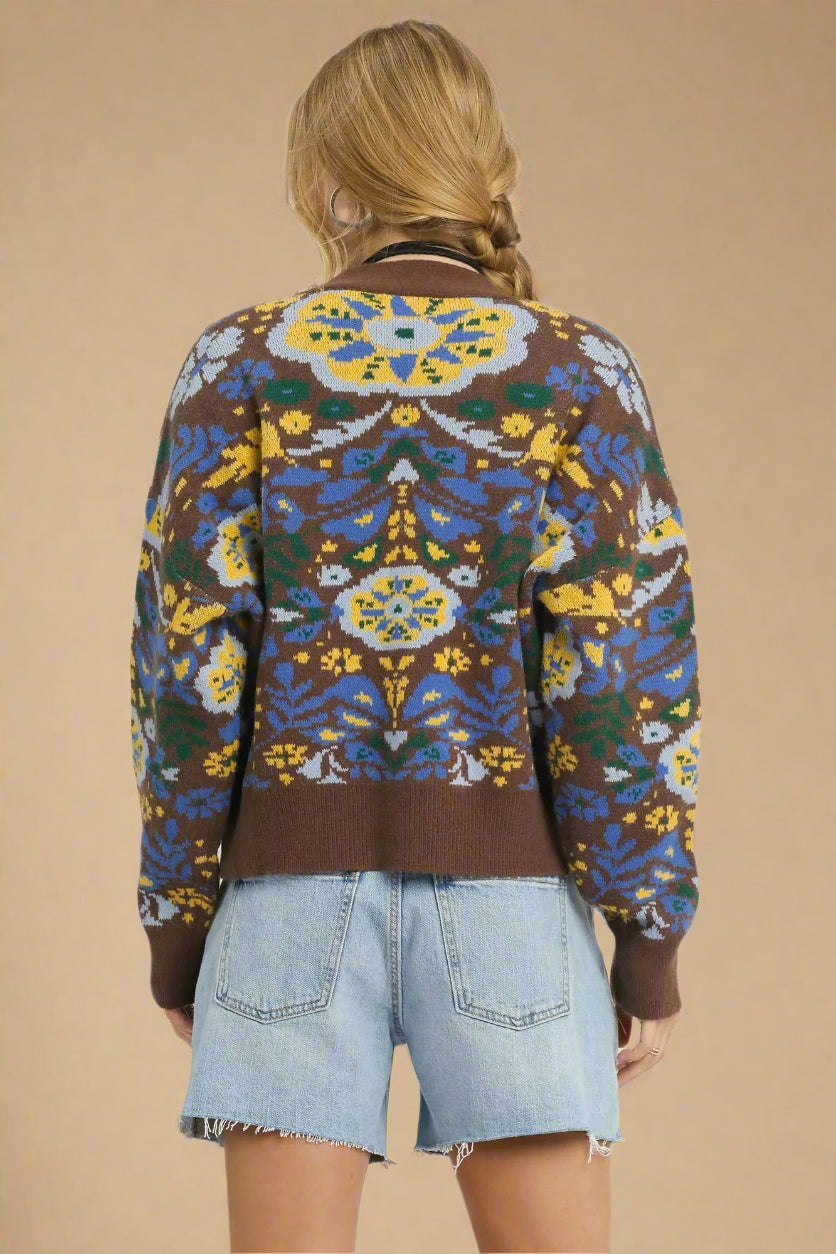 Person wearing a patterned cardigan with a beige background