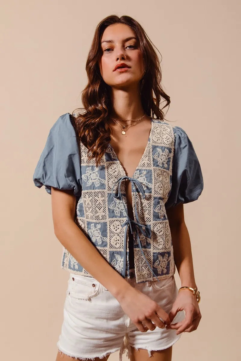 Woman wearing a patterned blouse and white shorts against a beige background