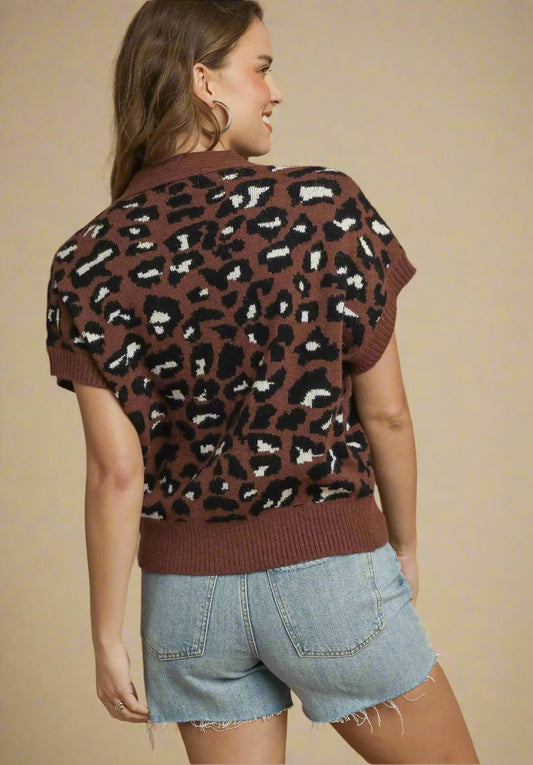 Woman wearing a brown leopard print sweater and denim shorts on a beige background