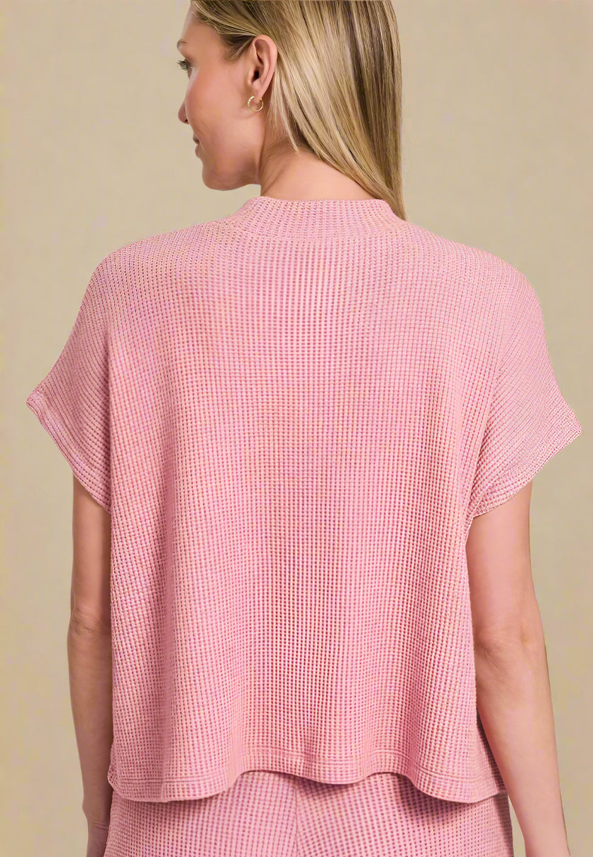 Woman wearing a light pink textured top on a beige background