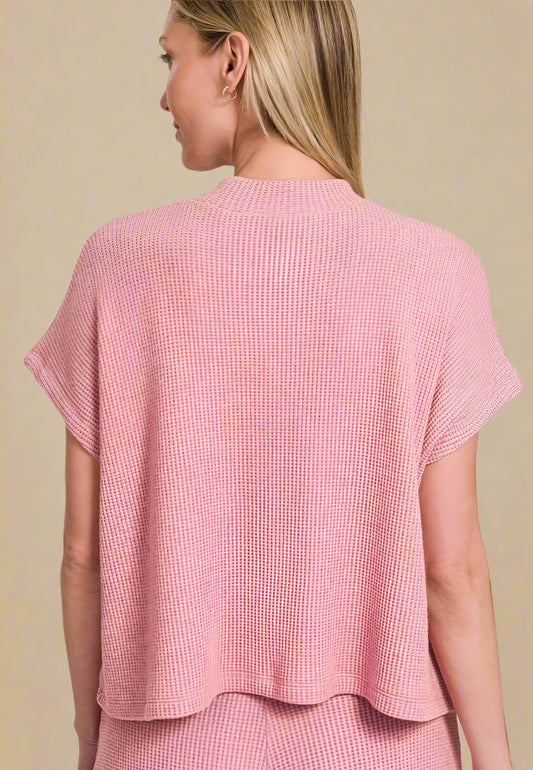 Woman wearing a light pink textured top on a beige background