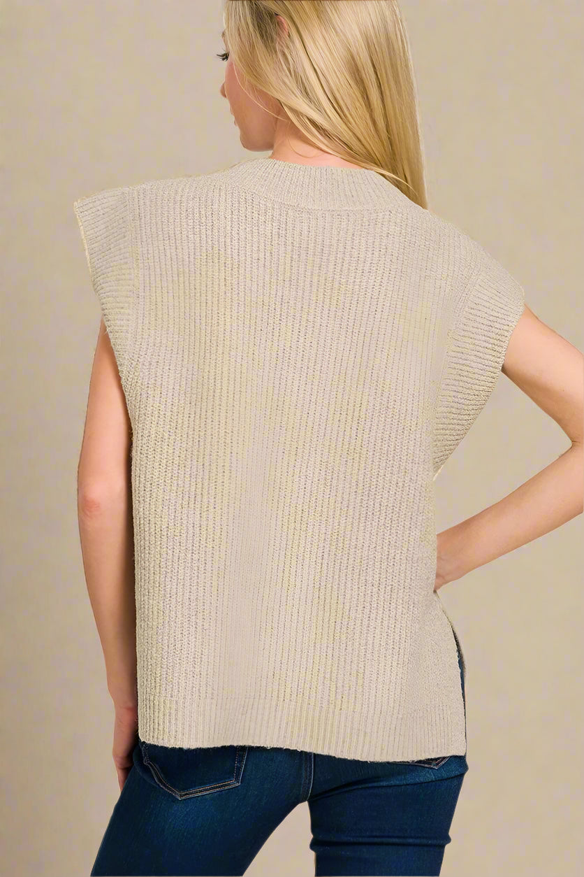 Woman wearing a beige sleeveless sweater on a white background