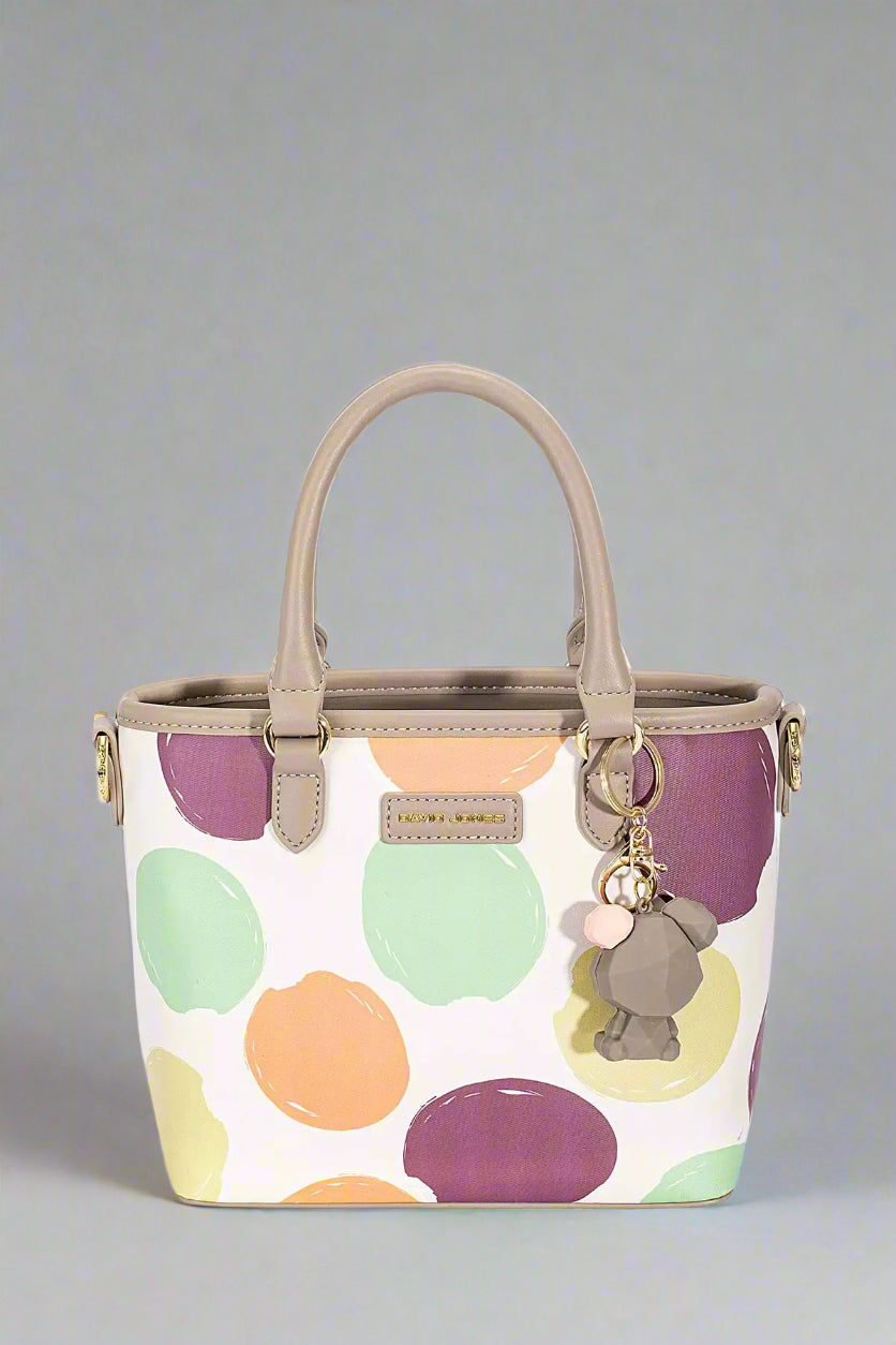 Handbag with colorful polka dot pattern and a keychain on a white background