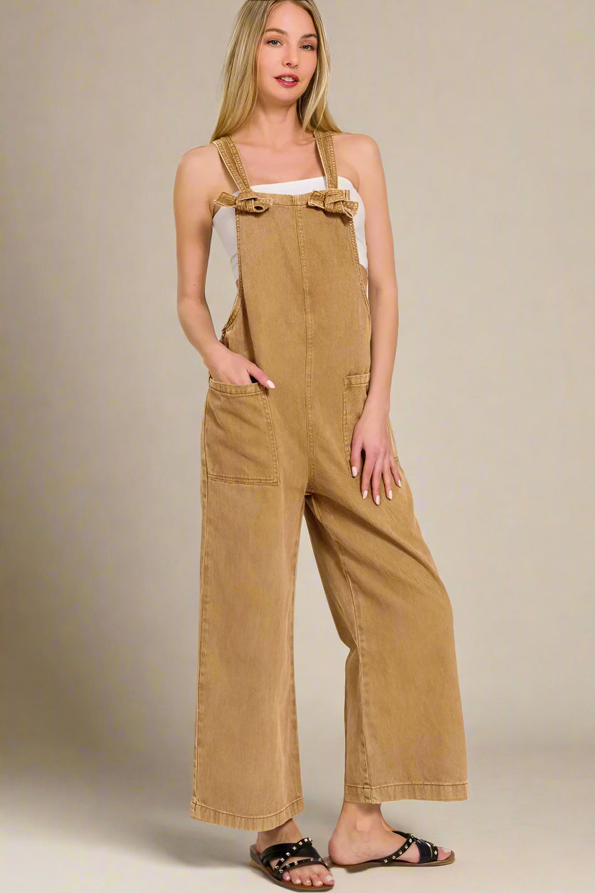 Woman wearing a deep camel colored overalls on a white background