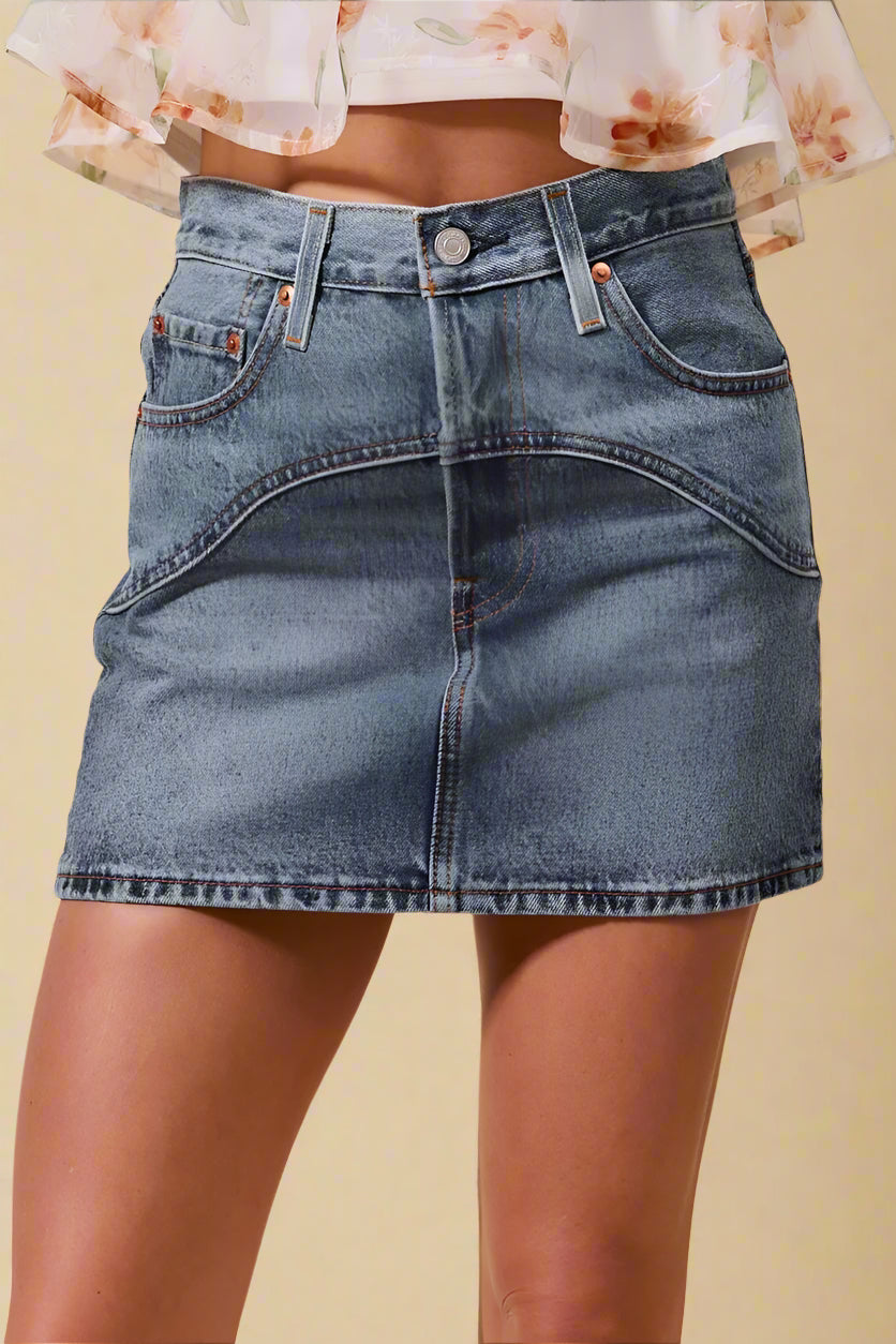 Blue denim skirt worn by a person on a beige background