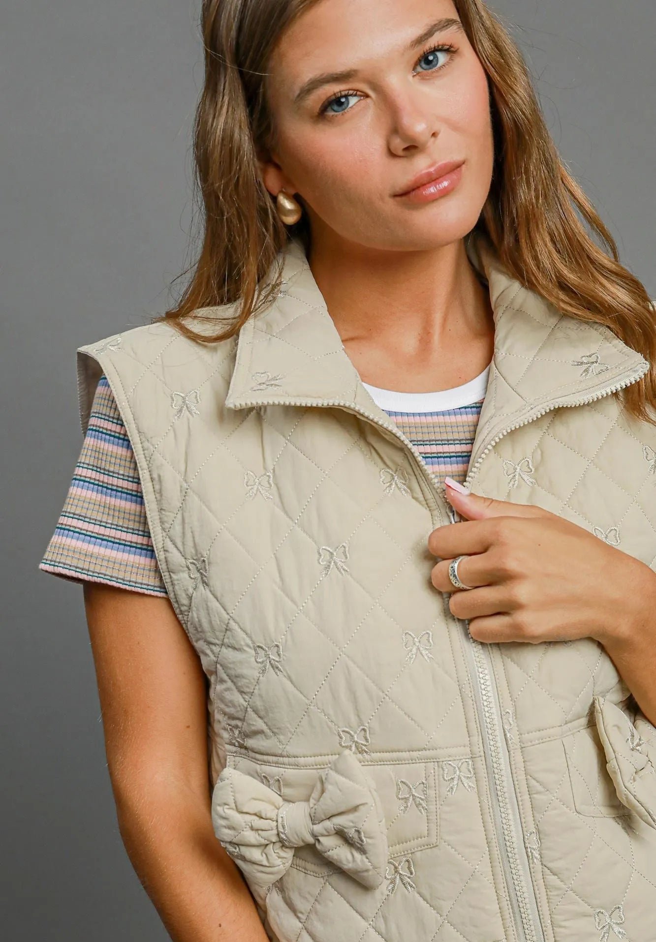 Woman wearing a beige quilted vest with a gray background
