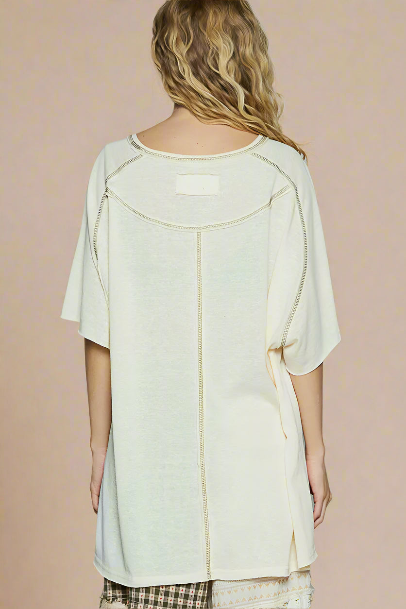 Woman wearing a light-colored top with a subtle pattern on a plain background