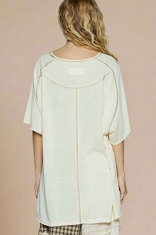 Woman wearing a light-colored top with a subtle pattern on a plain background