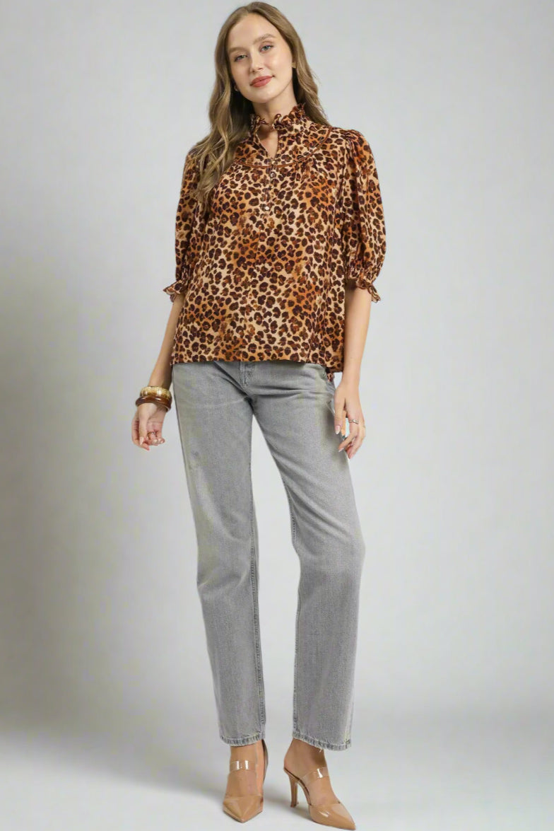 Woman wearing a leopard print blouse and gray pants on a white background