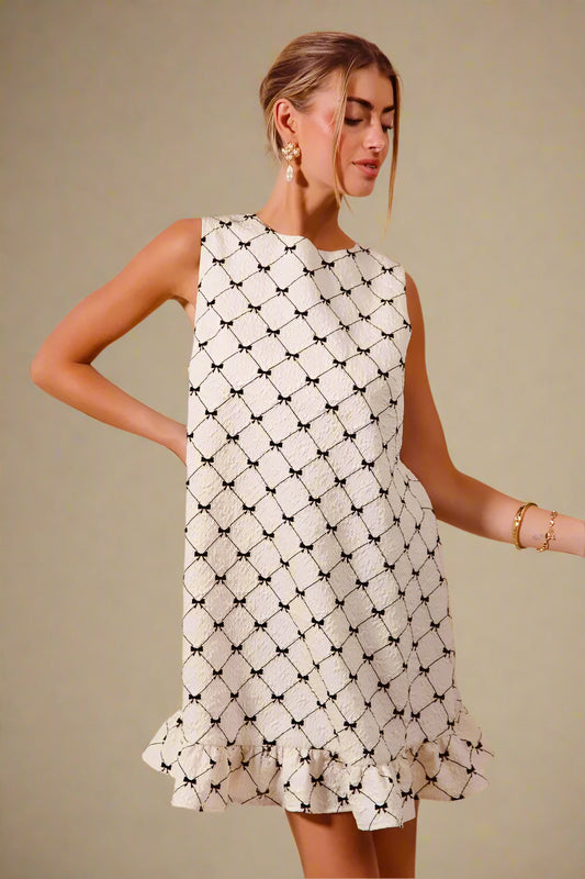 Woman wearing a white dress with black geometric pattern on a beige background