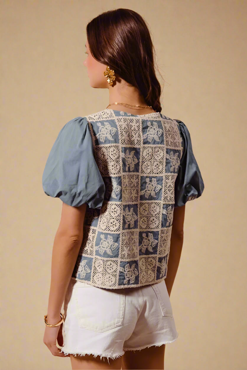 Woman wearing a patterned top with blue sleeves and beige background