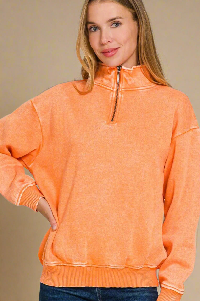 Woman wearing an orange pullover with a quarter zip on a beige background