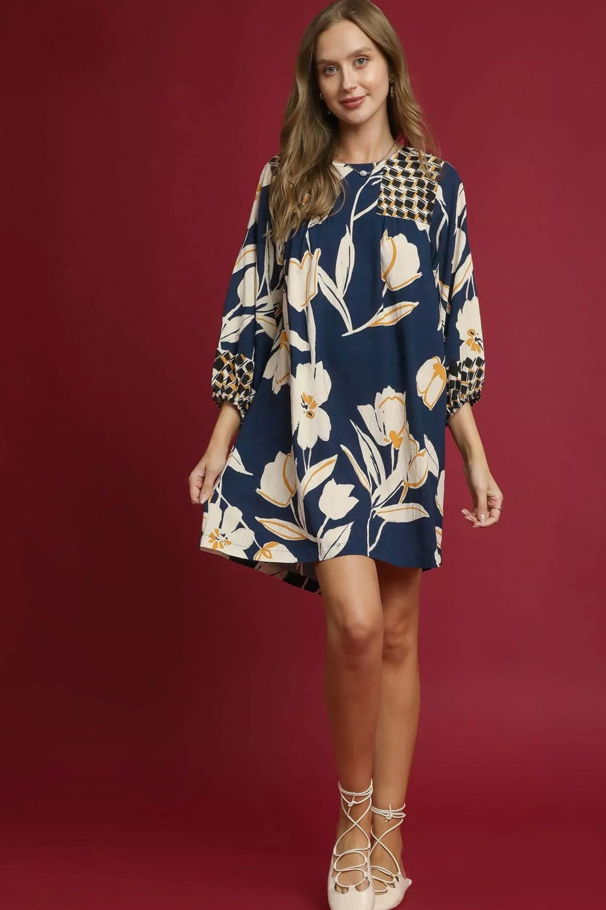 Woman wearing a floral dress with a checkered pattern on a red background