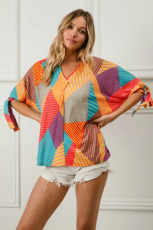 Woman wearing a colorful geometric patterned top against a white background