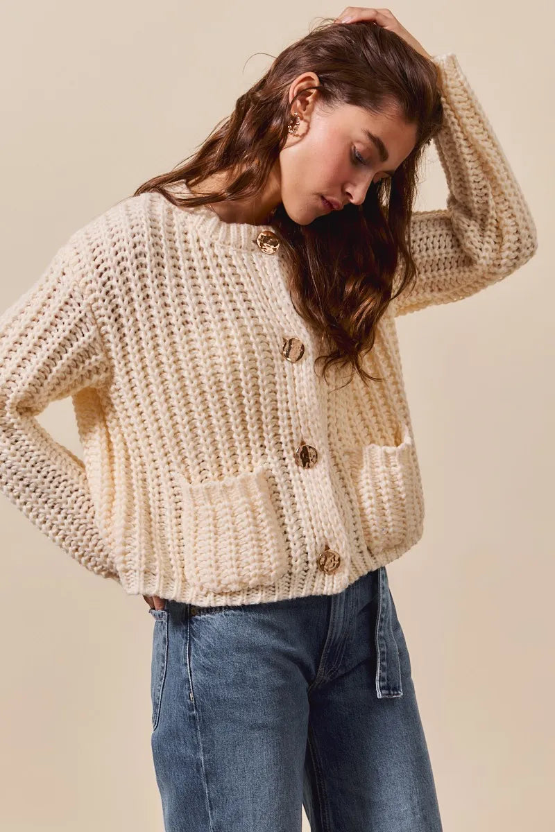 Woman wearing a beige knitted cardigan with buttons on a beige background