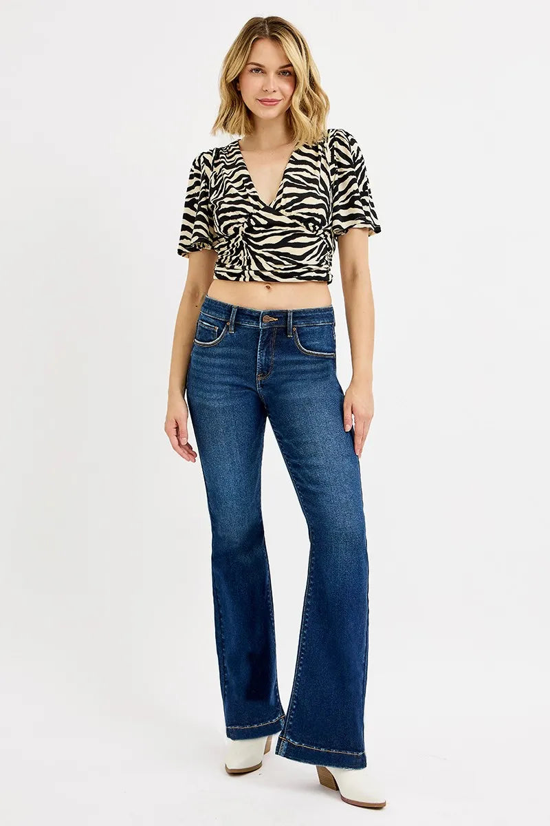 Woman wearing a zebra print top and blue jeans on a white background