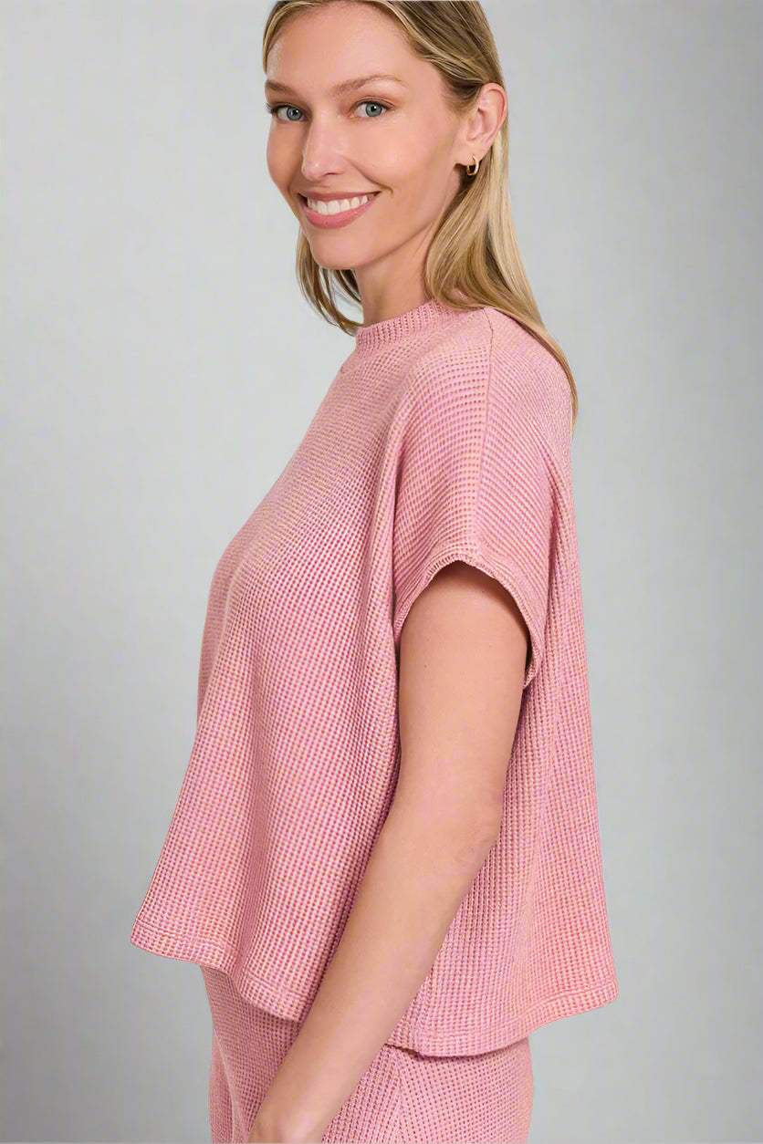 Woman wearing a light rose textured top on a white background
