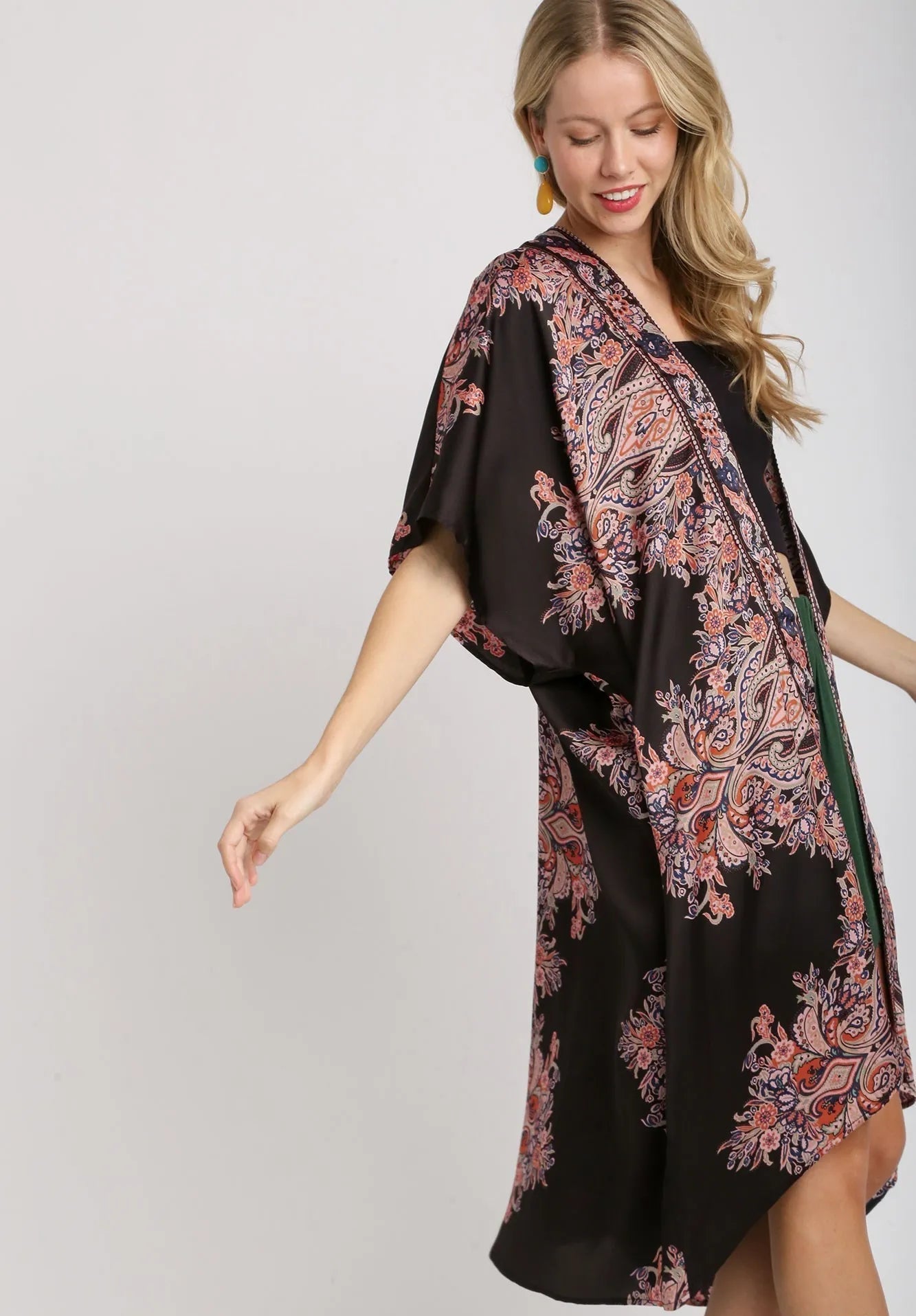 Woman wearing a black dress with a pink paisley patterned scarf on a white background