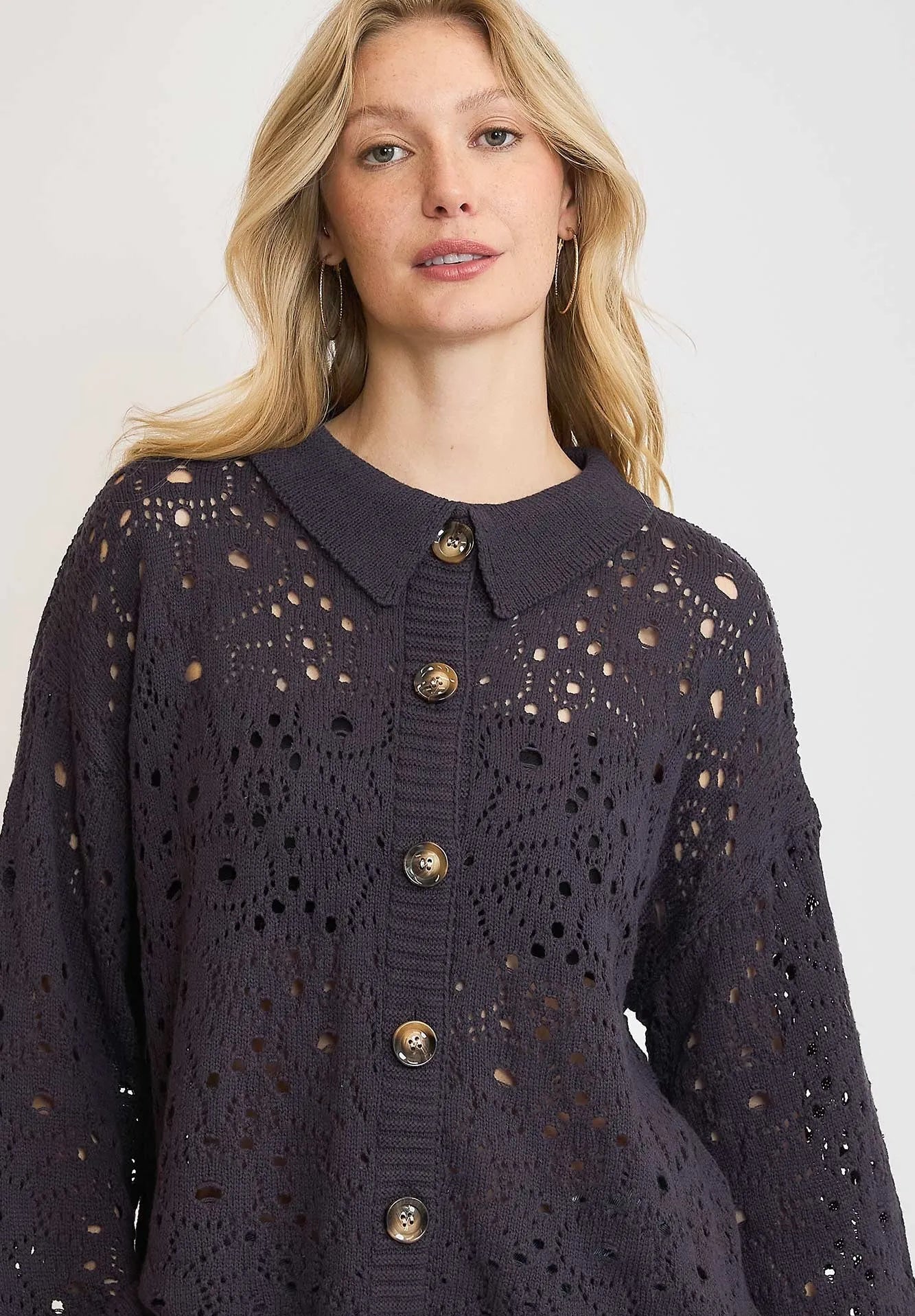 Woman wearing a dark blue knitted cardigan with gold buttons on a white background