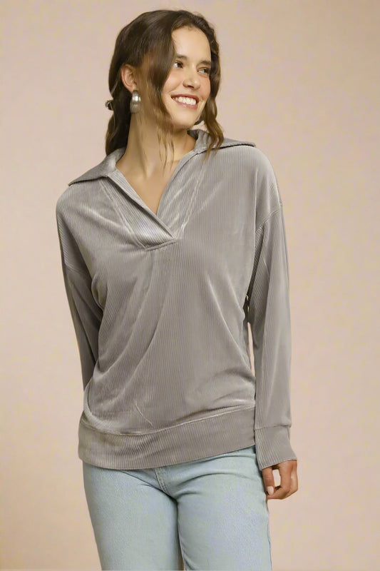 Woman wearing a gray long-sleeve top with a collar against a beige background