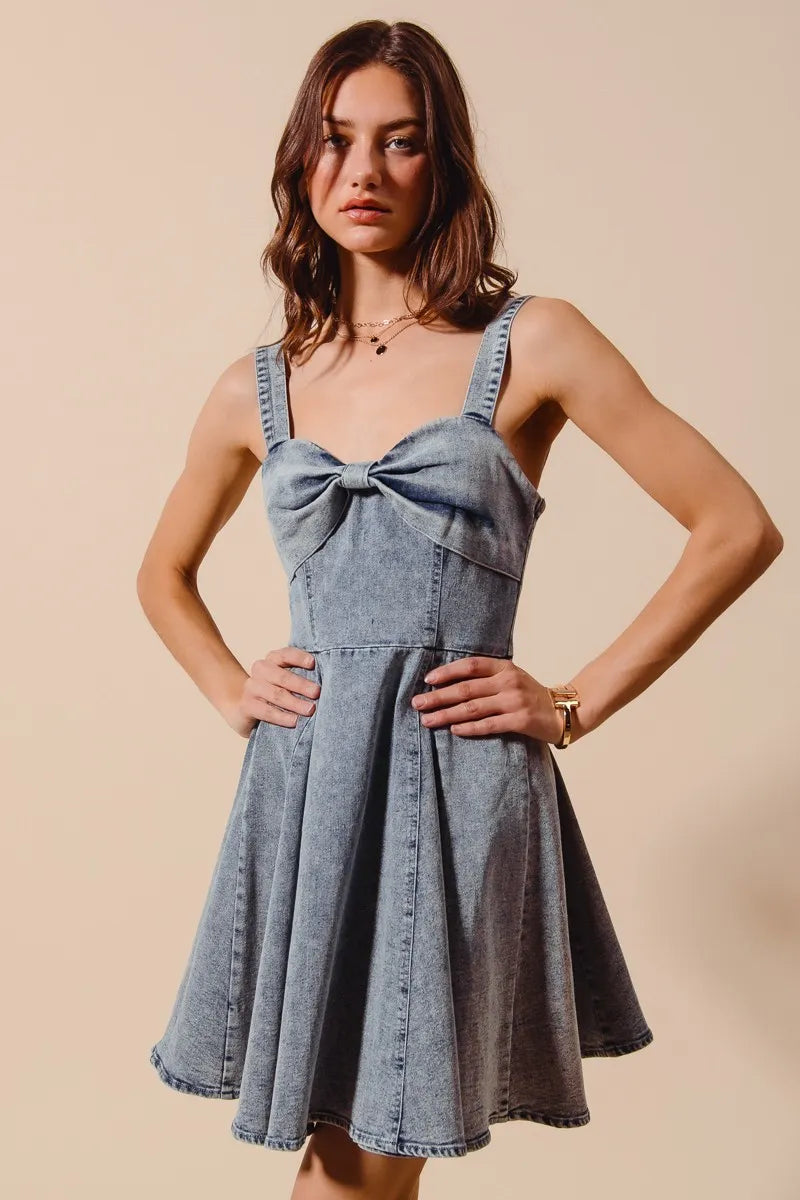Woman wearing a denim dress with a bow detail on a beige background