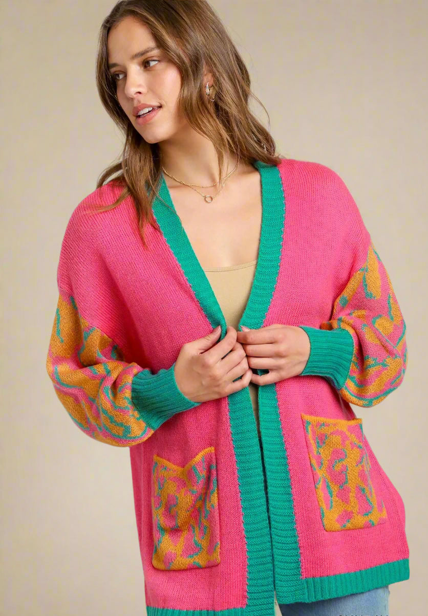 Woman wearing a colorful pink cardigan with abstract patterns on a plain background