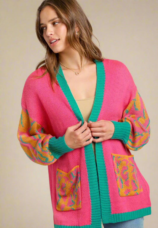 Woman wearing a colorful pink cardigan with abstract patterns on a plain background
