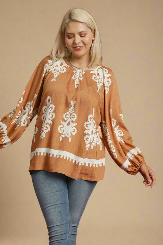 Woman wearing a brown blouse with white embroidery on a beige background
