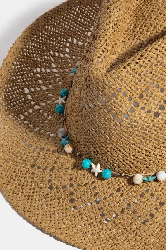 Close-up of a straw hat with decorative beads on a white background
