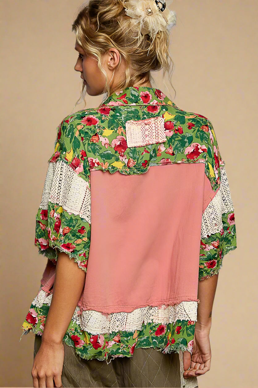 Person wearing a floral and pink layered shirt against a gray background