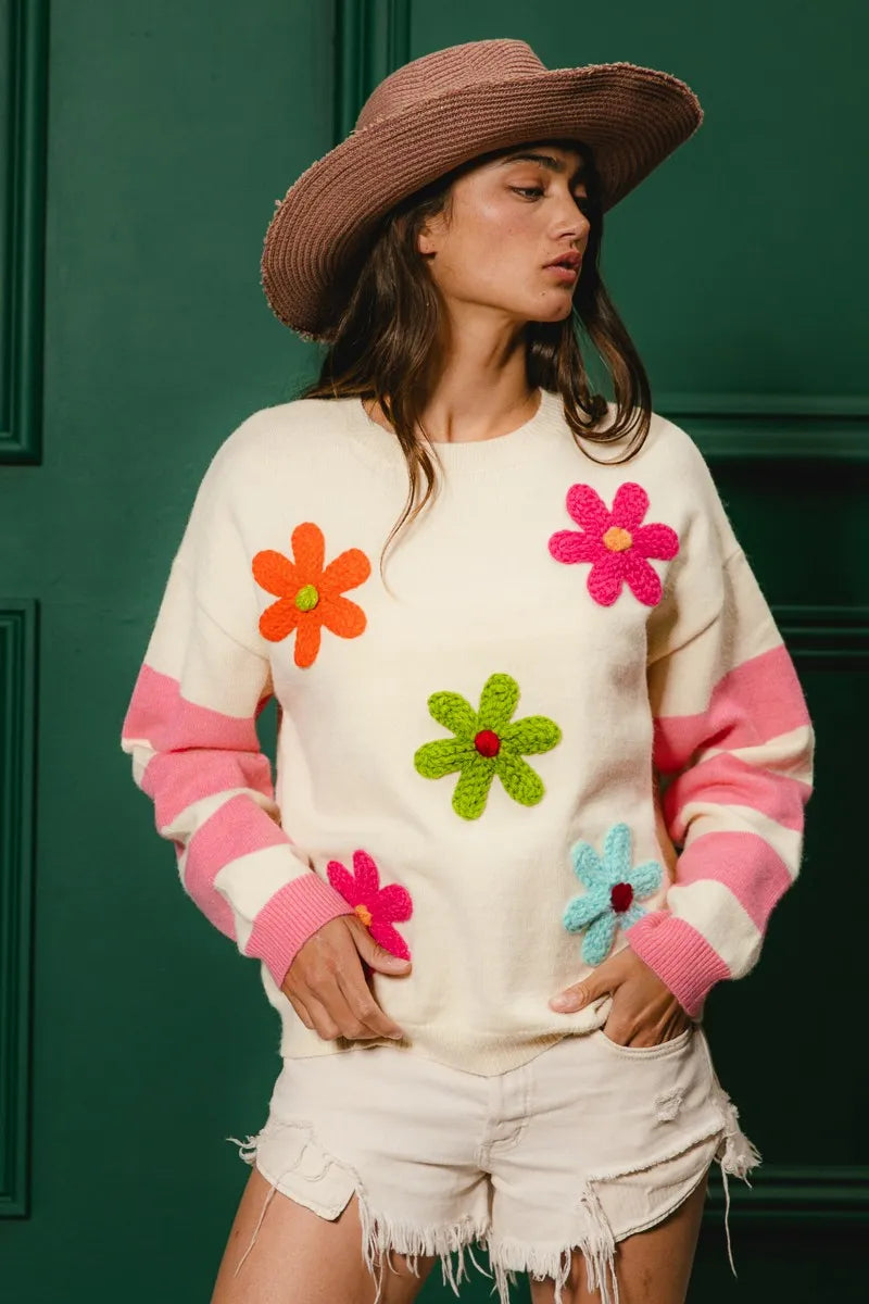Woman wearing a sweater with colorful flower designs against a green background