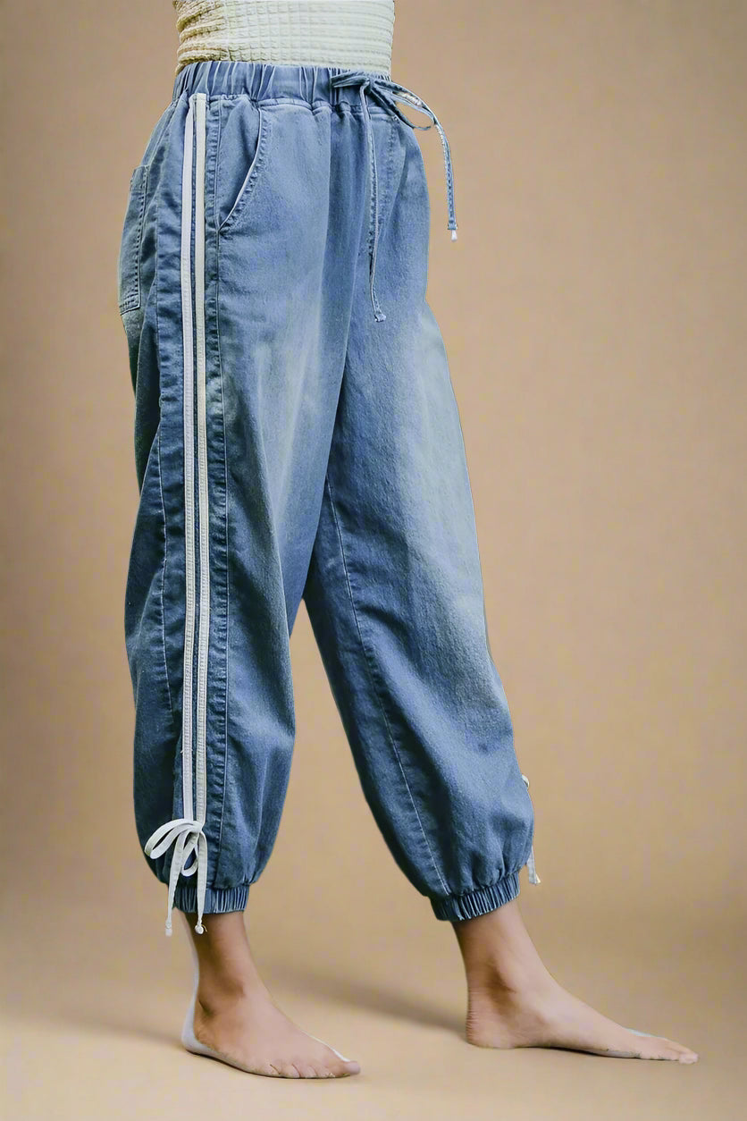 Person wearing blue pants with white stripes standing on a beige background