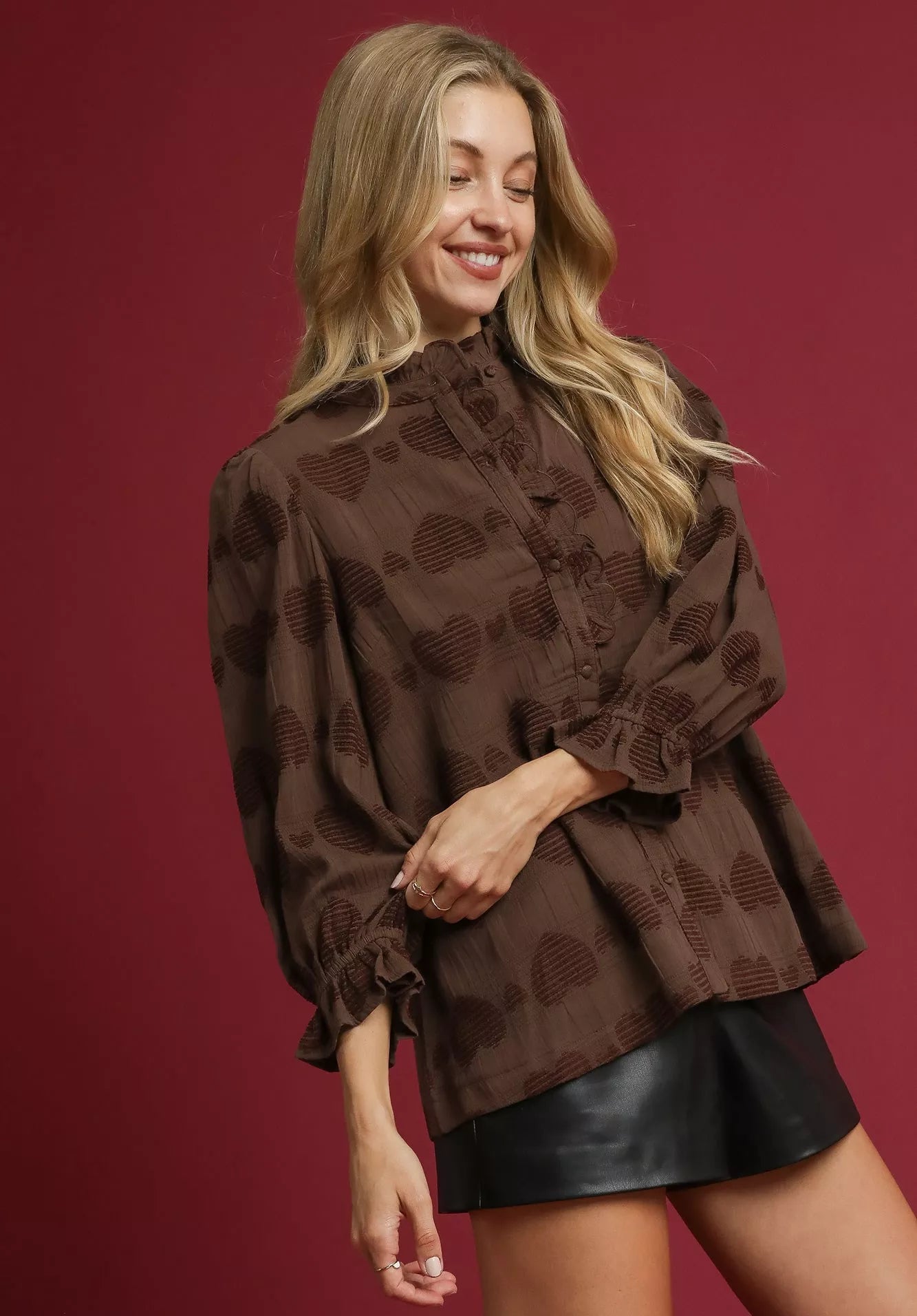 Woman wearing a brown patterned blouse and black skirt on a red background