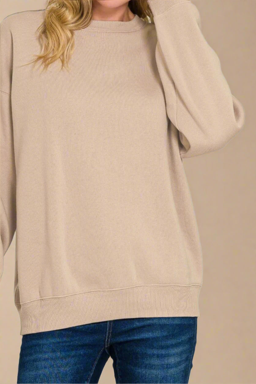 Beige sweater worn by a person with blue jeans on a beige background