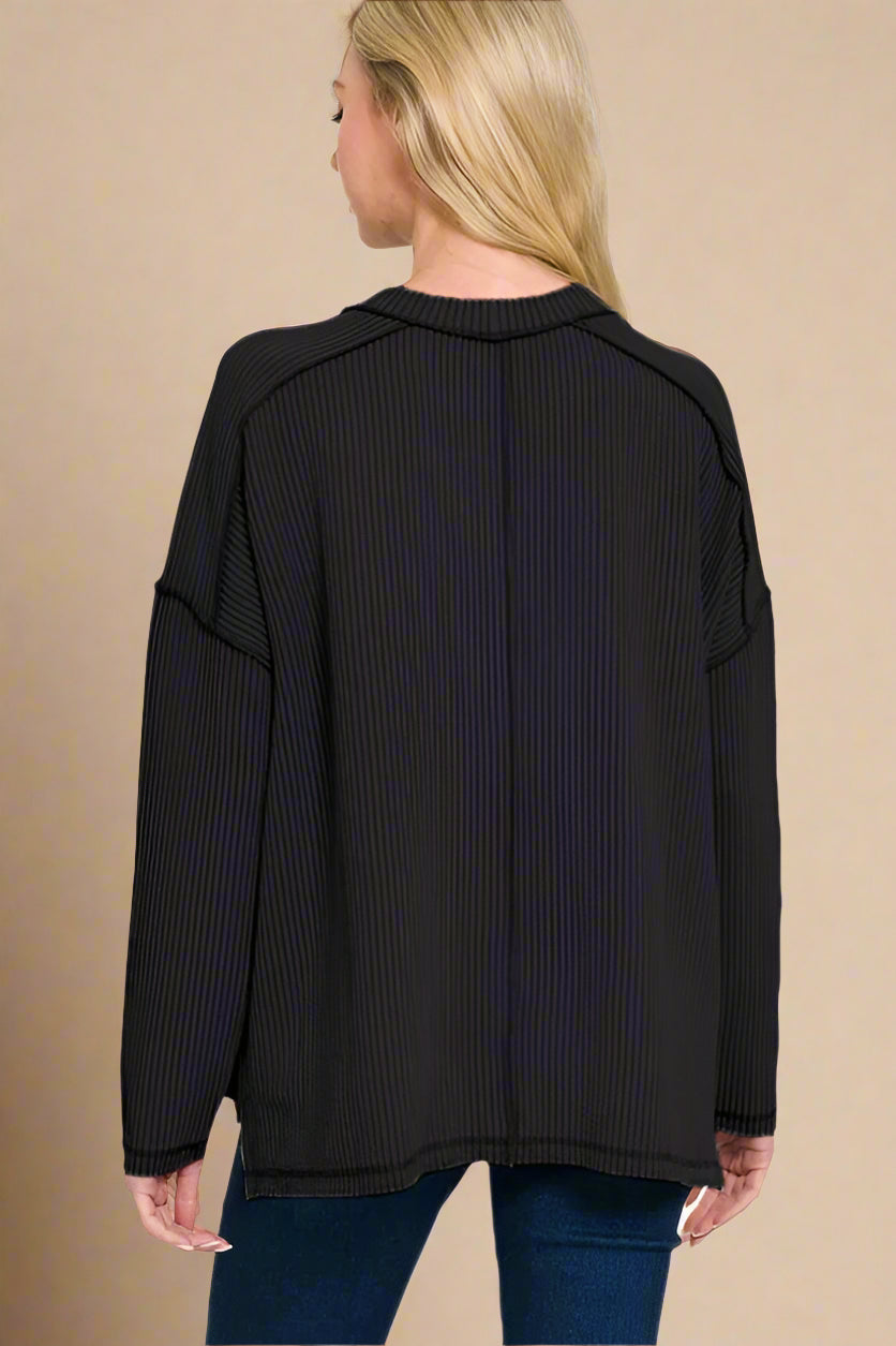 Black ribbed sweater worn by a person on a beige background