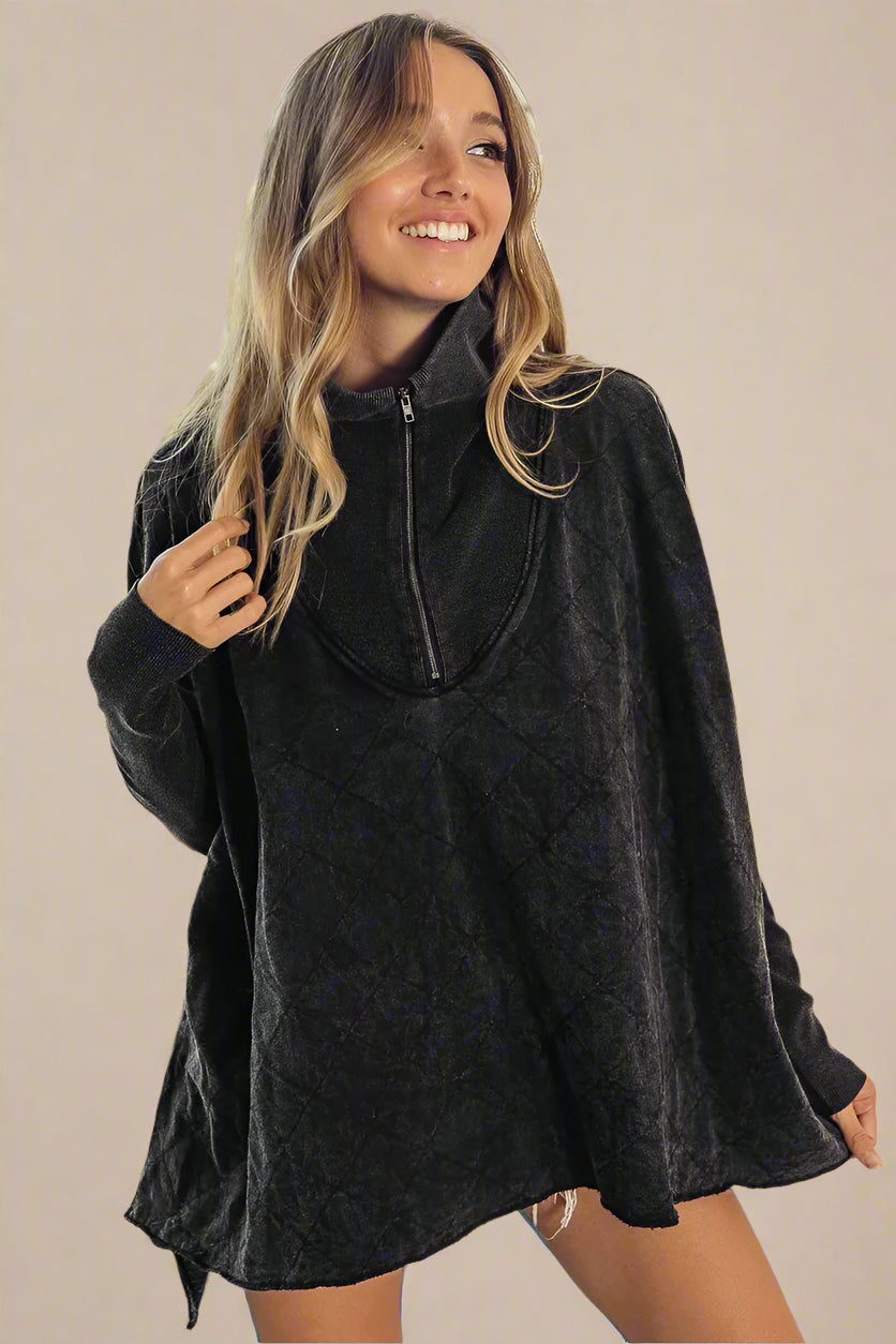 Woman wearing a dark gray poncho top with a zipper
