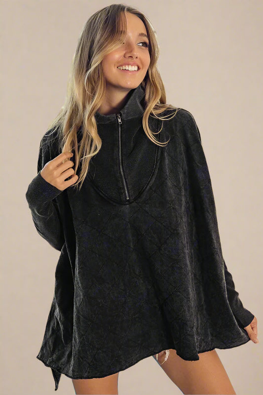 Woman wearing a dark gray poncho top with a zipper