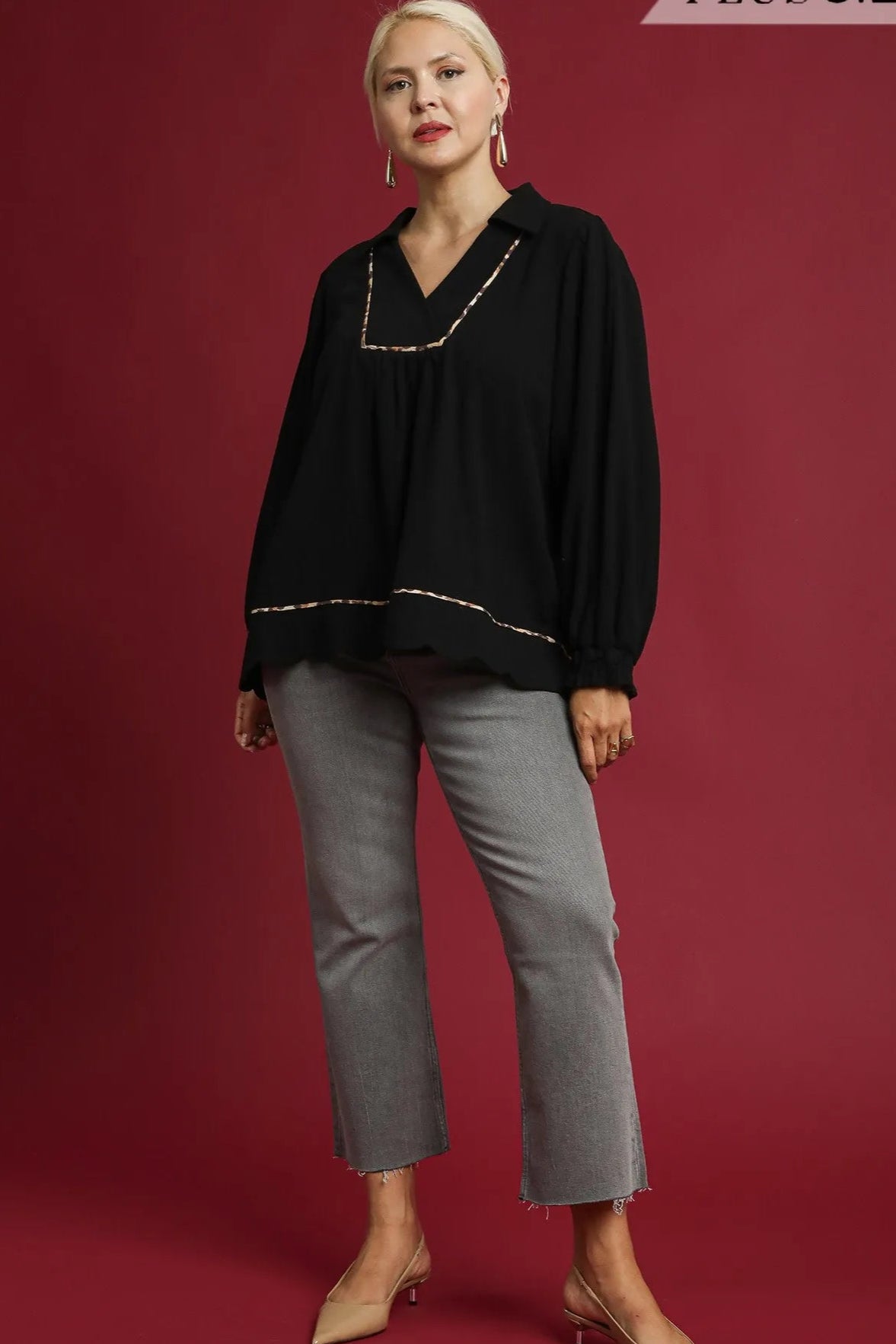 Woman wearing a black blouse and gray pants on a red background with 'Plus Size' text.