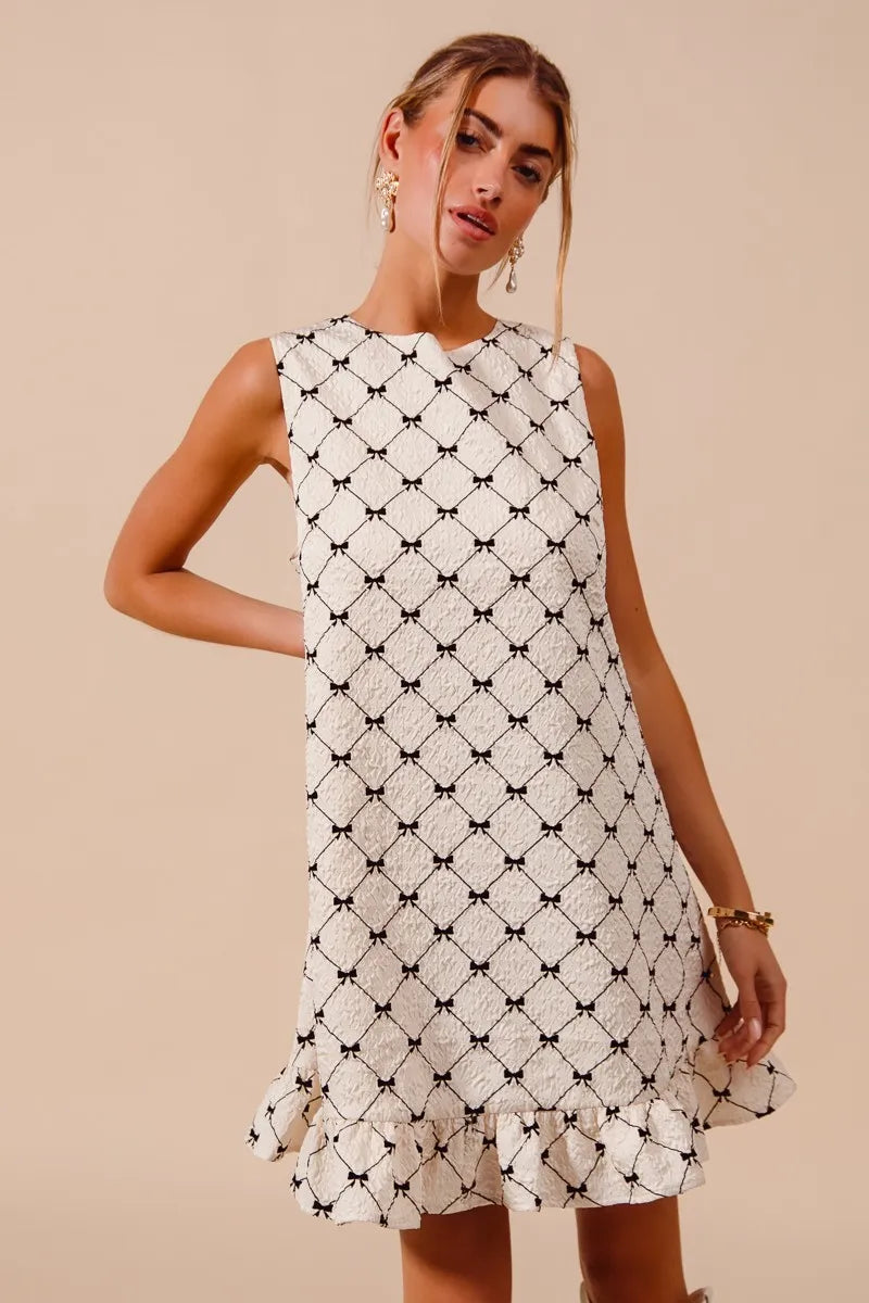 Woman wearing a white dress with black geometric pattern on a beige background