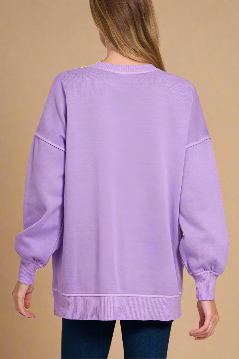Person wearing a lavender sweater on a beige background