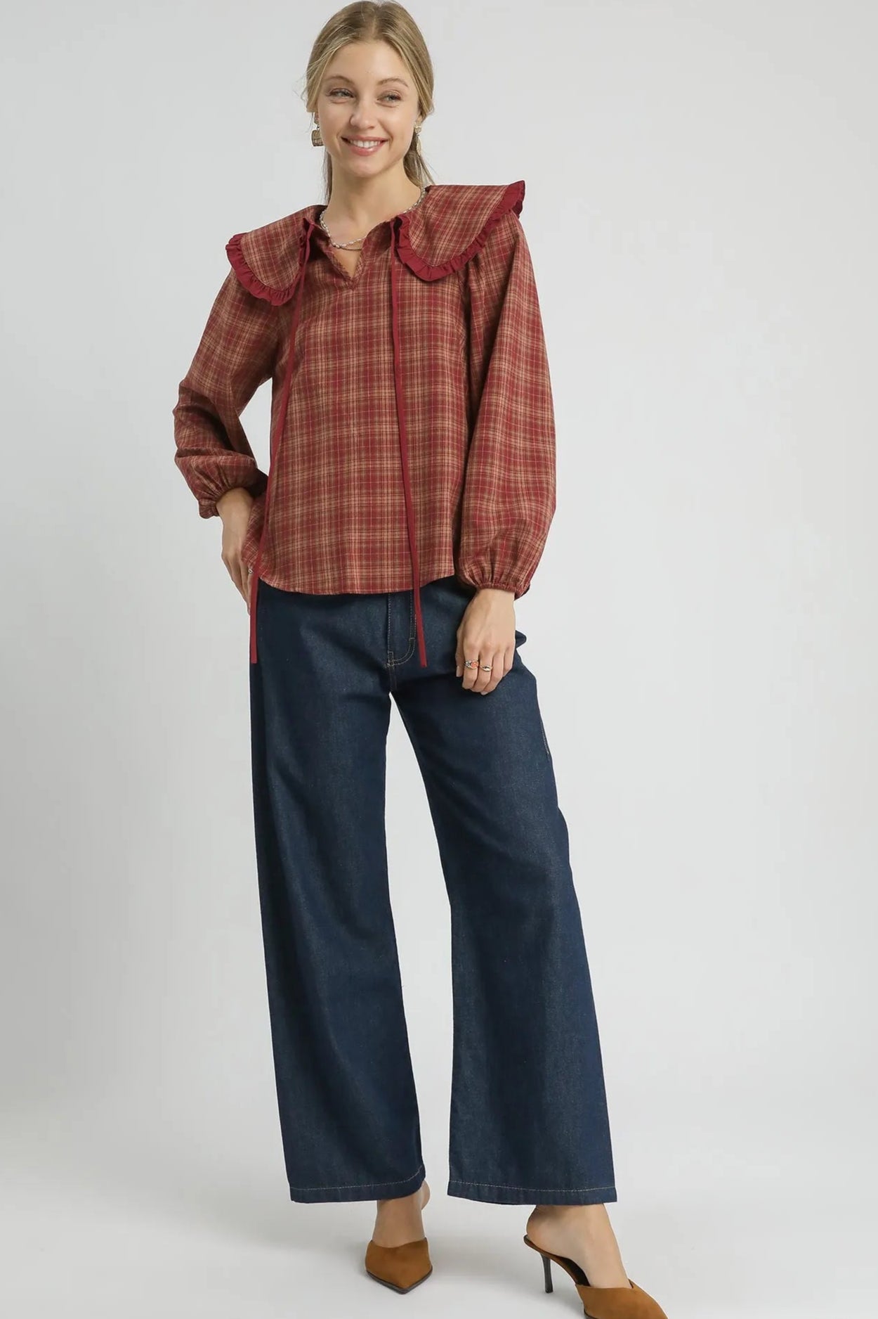 Woman wearing a red plaid blouse and blue jeans on a white background