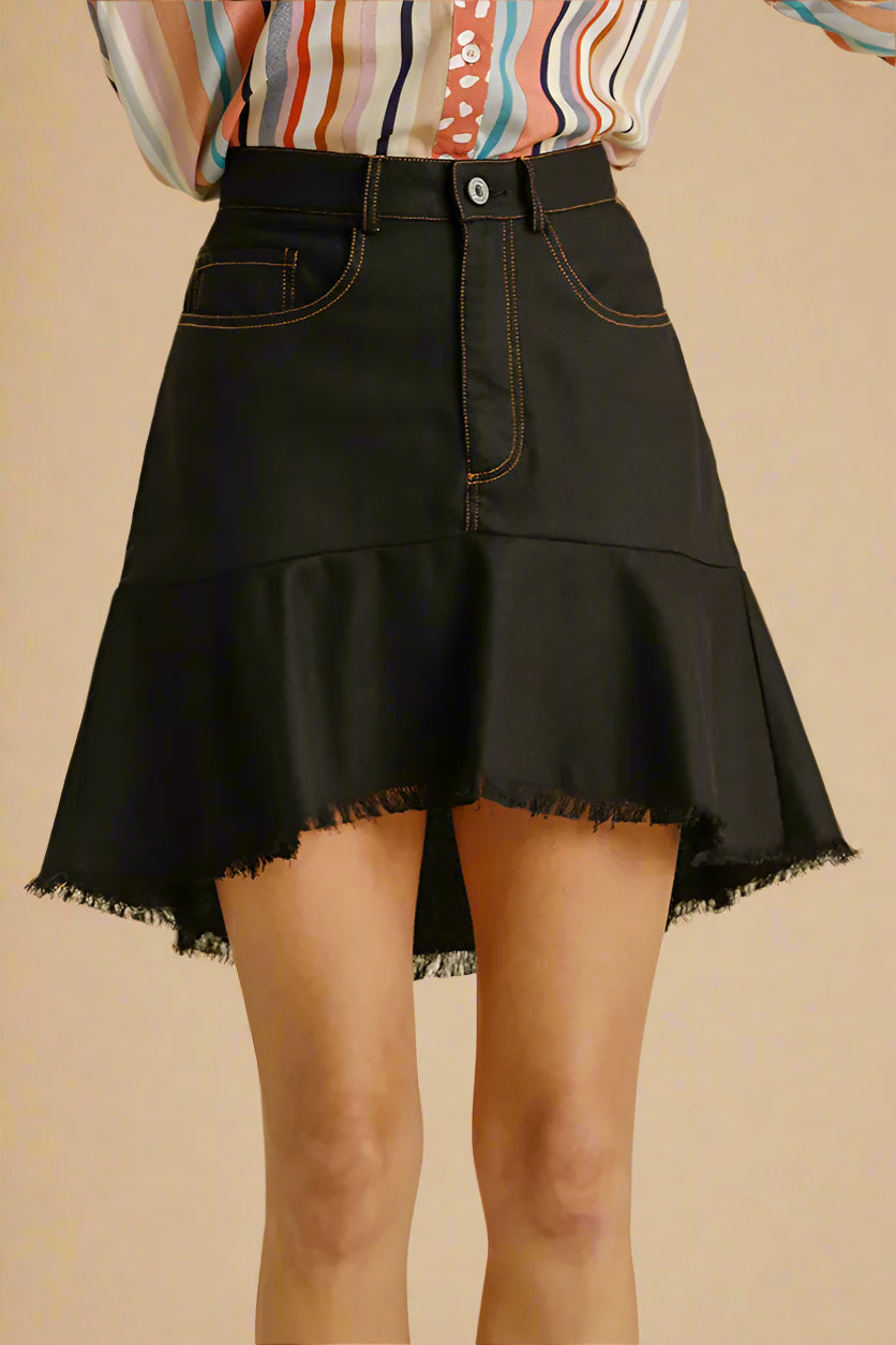 Black denim skirt worn by a person on a beige background