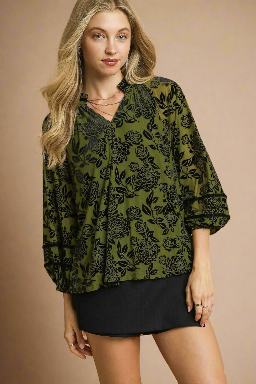 Woman wearing a green patterned blouse with a beige background