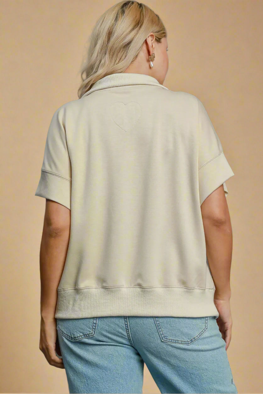 Person wearing a beige top and blue jeans on a gray background