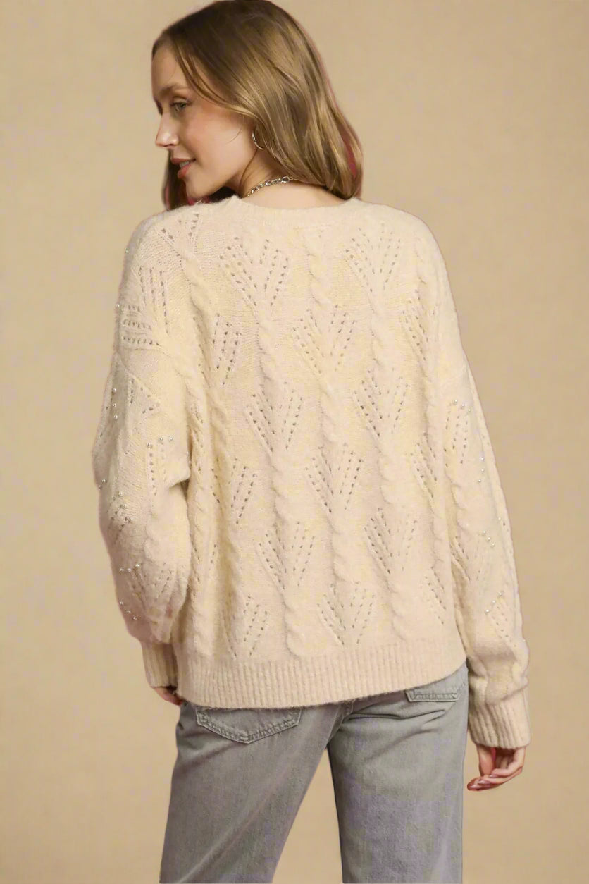 Woman wearing a cream sweater against a red background