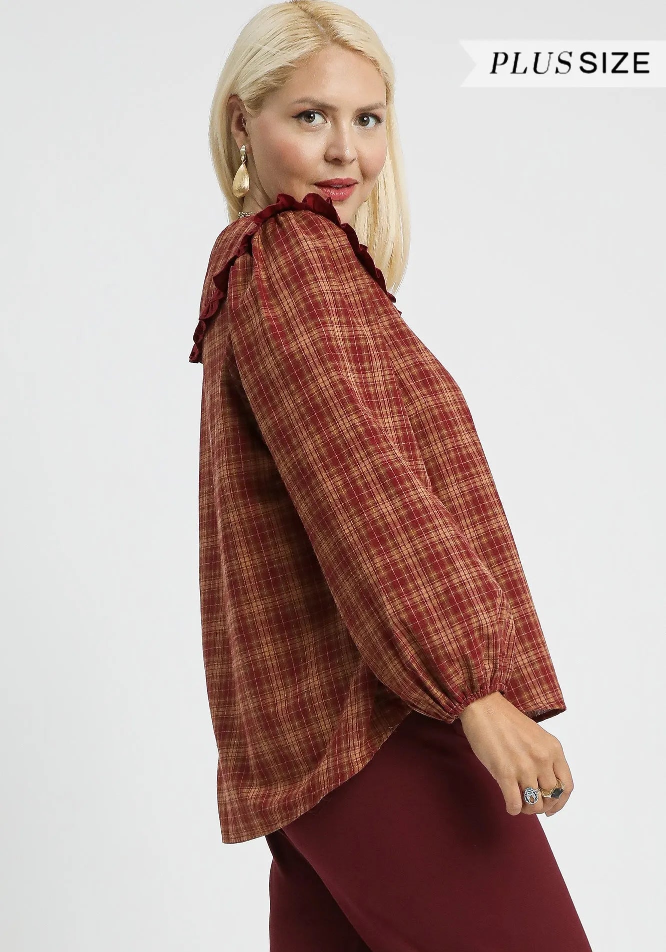 Woman wearing a plaid blouse with puffed sleeves on a white background