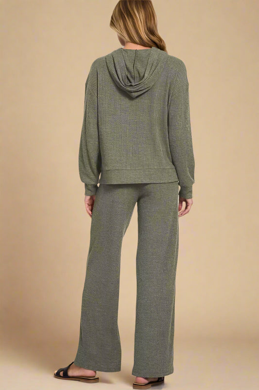 Person wearing a green hoodie and pants set on a white background